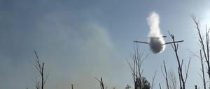 Ein kleines Löschflugzeug wirft Wasser ab über einem Waldbrand in einem munitionsbelasteten Gebiet bei Jüterbog (Landkreis Teltow-Fläming). Der Waldbrand hat sich trotz des Löscheinsatzes aus der Luft auf rund 27 Hektar ausgebreitet.
