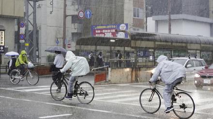 Mehr als nur Regen. Radfahrer in der südjapanischen Stadt Kochi bringen sich in Sicherheit.