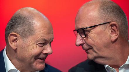 Bundeskanzler Olaf Scholz (l, SPD), und Dietmar Woidke (SPD), Ministerpräsident von Brandenburg, unterhalten sich während der Landesvertreterversammlung der SPD.