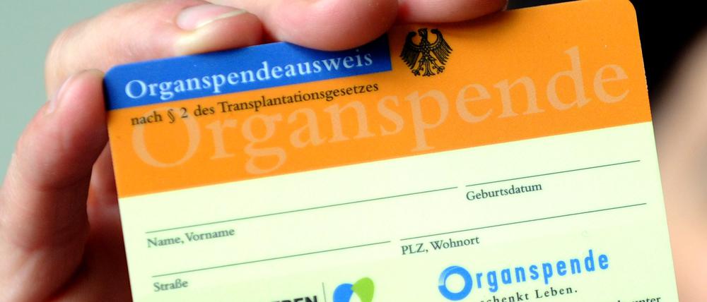 Eine Frau hält einen Organspendeausweis in der Hand. 