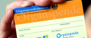 Eine Frau hält einen Organspendeausweis in der Hand.
