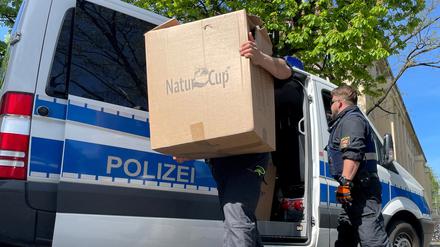 Ein Polizist trägt Kisten auf eine Polizeiwache.