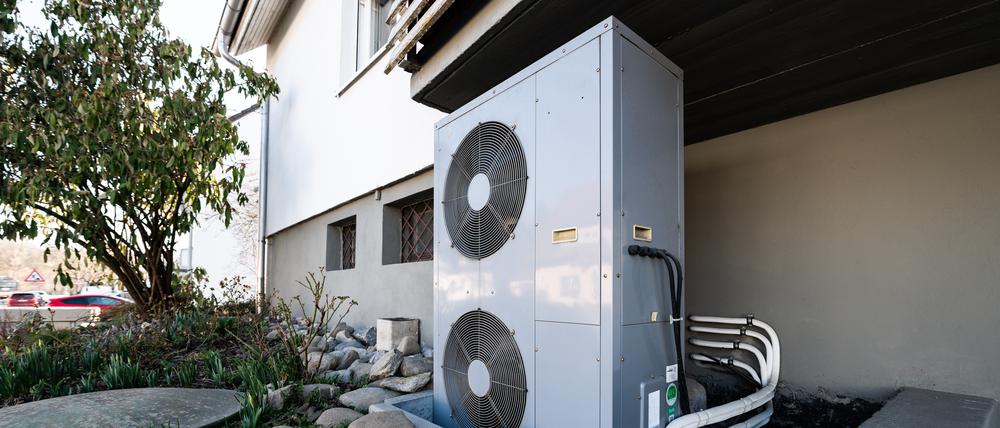 Die Lüftungsanlage einer Wärmepumpe steht vor einem Wohnhaus.