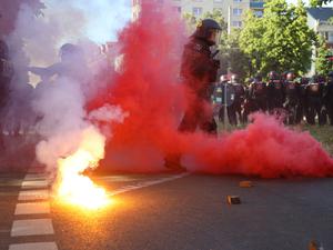 Bei Protesten gegen das Urteil im Prozess gegen Lina E. in Leipzig stehen Polizisten in rotem Qualm, nachdem linke Demonstranten Pyrotechnik gezündet und geworfen hatten.