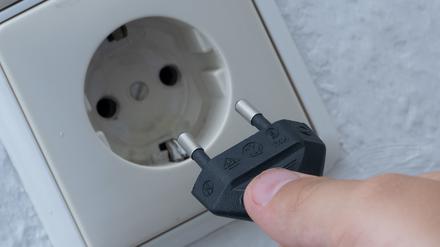 Ein Mann steckt einen Stecker in eine Steckdose.