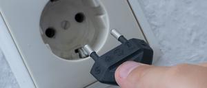 Ein Mann steckt einen Stecker in eine Steckdose.