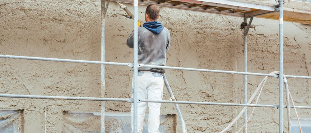 Worker plastering outer wall of newly built house