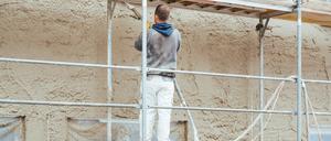 Worker plastering outer wall of newly built house