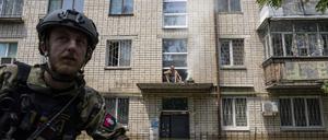 Cherson. Ein Mann kocht auf einem offenen Feuer auf einer Veranda vor dem Eingang eines mehrstöckigen Gebäudes in einem überfluteten Viertel. 