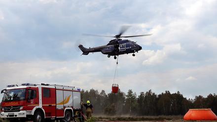 08.06.2023, Brandenburg, Jüterbog: Ein Löschhubschrauber ist in einem Waldstück nahe Jüterbog im Einsatz. Die Lage beim Waldbrand auf dem ehemaligen Truppenübungsplatz bei Jüterbog hat sich etwas entspannt. Foto: Sven Kaeuler/TNN/dpa +++ dpa-Bildfunk +++