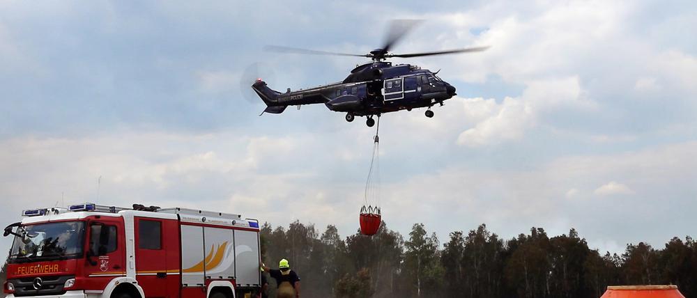 08.06.2023, Brandenburg, Jüterbog: Ein Löschhubschrauber ist in einem Waldstück nahe Jüterbog im Einsatz. Die Lage beim Waldbrand auf dem ehemaligen Truppenübungsplatz bei Jüterbog hat sich etwas entspannt. Foto: Sven Kaeuler/TNN/dpa +++ dpa-Bildfunk +++
