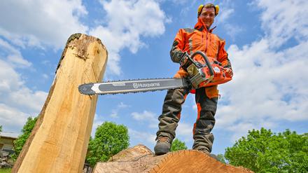 Christian Mücke, Kettensägen-Künstler, steht mit einer Motorsäge auf einem großen Eichenstamm. Speedcarving nennt sich die Kettensägenkunst, bei der in vorgegebener Zeit Skulpturen aus Holzstämmen entstehen.