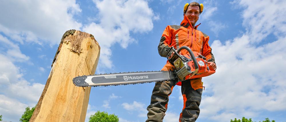 Christian Mücke, Kettensägen-Künstler, steht mit einer Motorsäge auf einem großen Eichenstamm. Speedcarving nennt sich die Kettensägenkunst, bei der in vorgegebener Zeit Skulpturen aus Holzstämmen entstehen.