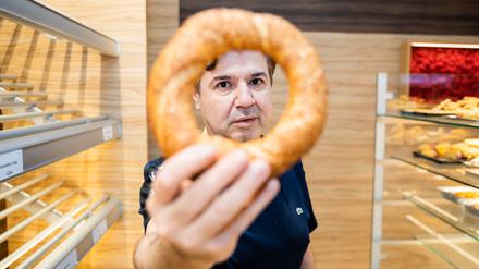 Bäckereiinhaber Mehmet Cevik hält in seiner türkischen Cevik-Bäckerei in Berlin-Wedding einen Simit in die Kamera.