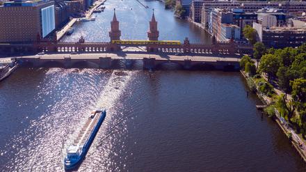Ein Ausflugsschiff fährt unweit der Oberbaumbrücke auf der Spree in Richtung Innenstadt.