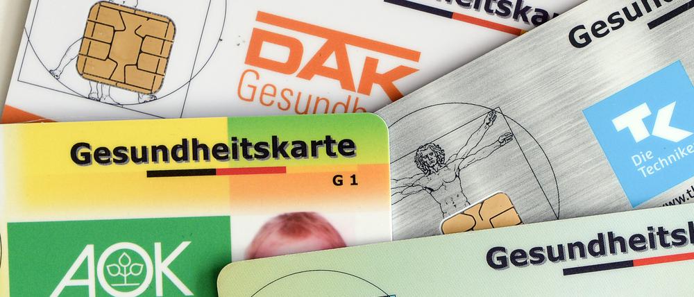Mehrere Karten von Krankenversicherungen liegen auf einem Tisch.