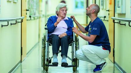 Ein Altenpfleger unterhält sich mit einer Bewohnerin.