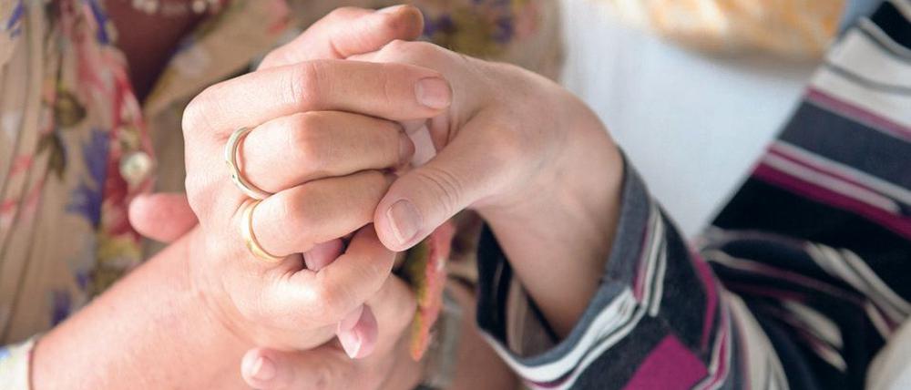Eine Therapeutin (l) hält in einem Hospiz in Stuttgart (Baden-Württemberg) die Hand einer todkranken Bewohnerin.