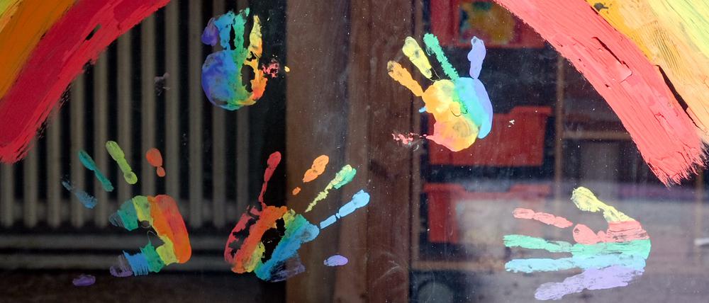 Kinderhände und ein Regenbogen sind an einer Kita zu sehen (Symbolbild).