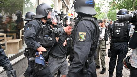 Polizisten halten einen Teilnehmer aus einer Demonstration in Leipzig fest.