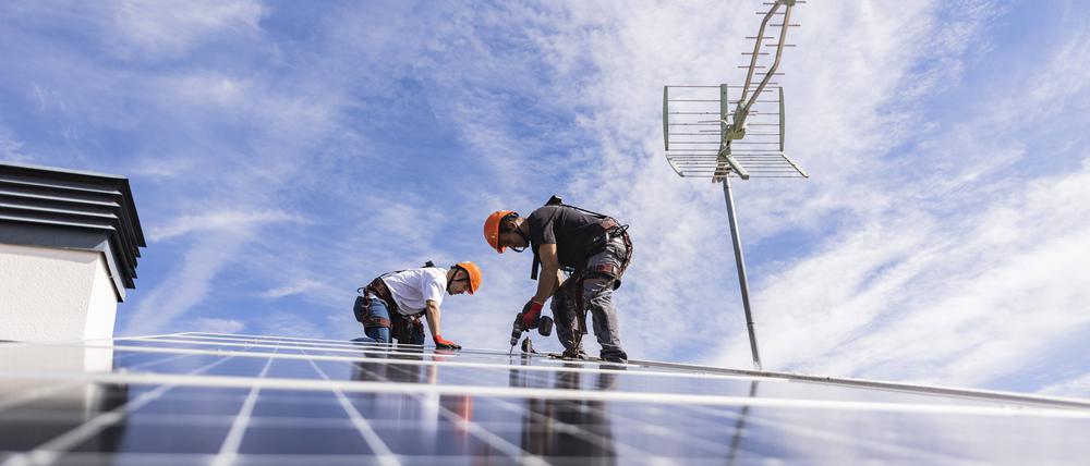 Handwerker montieren Solarpaneele (Symbolbild)