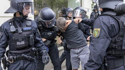 Demo in Leipzig. Polizisten halten einen Teilnehmer fest.