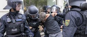 Demo in Leipzig. Polizisten halten einen Teilnehmer fest.