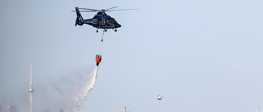 Ein Hubschrauber der Bundespolizei wirft im August 2022 Wasser über der Brandstelle im Grunewald ab.