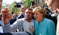 Selfie mit der Kanzlerin: Beim Besuch der Außenstelle des Bundesamts für Migration in Spandau bittet ein Syrer Angela Merkel um ein Foto.