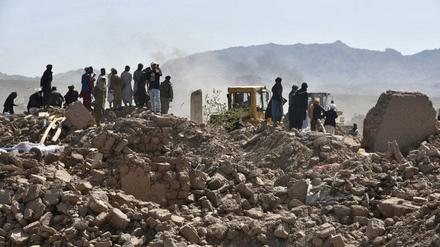 Überlebende des Erdbebens in Afghanistan stehen neben den Resten von zerstörten Häusern. 
