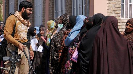 Ein Taliban-Mitglied mit wartenden Frauen in Herat. 
