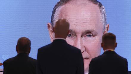 Männer schauen auf einen Bildschirm, der die Ansprache von Russlands Präsident Putin bei der Plenarsitzung des Russisch-Afrikanischen Wirtschafts- und Humanitären Forums überträgt. 