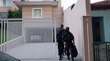 Polizisten kommen nach dem Haftbefehl aus dem Haus des Sicherheitschefs.
