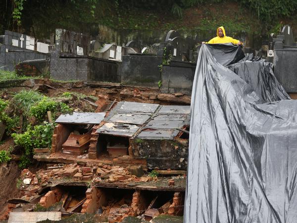 Ein Arbeiter deckt freigelegte Särge ab, nachdem der Friedhof in Petrópolis durch heftige Niederschläge schwer beschädigt wurde.