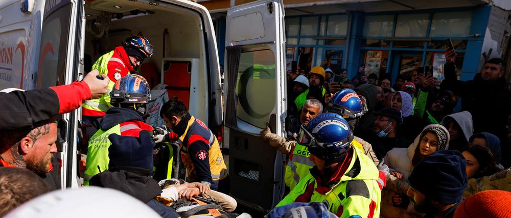 Rettungskräfte bringen die aus den Trümmern gerettete Frau in einen Krankenwagen.