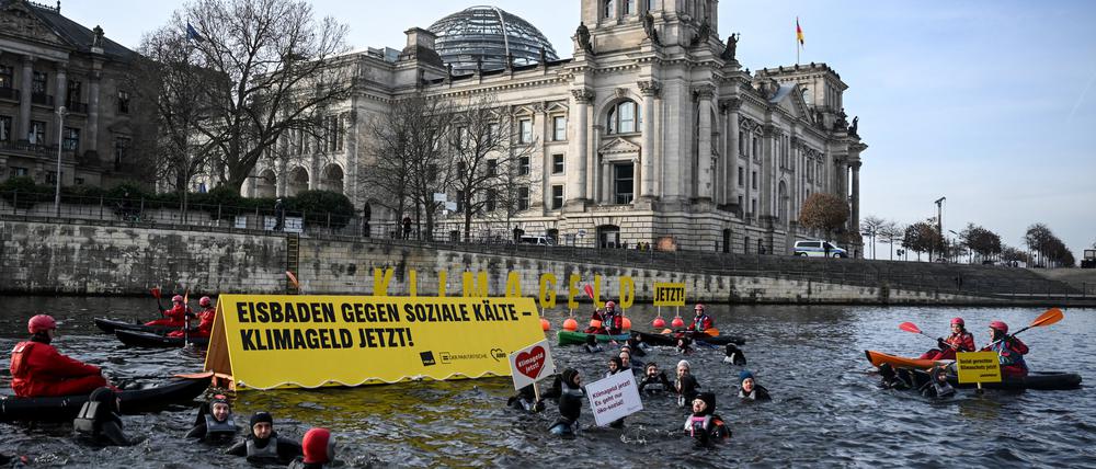 Aktivisten von verdi, AWO, dem Paritätischen und Greenpeace schwimmen und paddeln in der Spree. Sie zeigen Plakate mit der Aufschrift «Klimageld Jetzt!» und «Eisbaden gegen soziale Kälte - Klimageld jetzt!». Demonstriert wird für eine schnelle Einführung des Klimagelds.