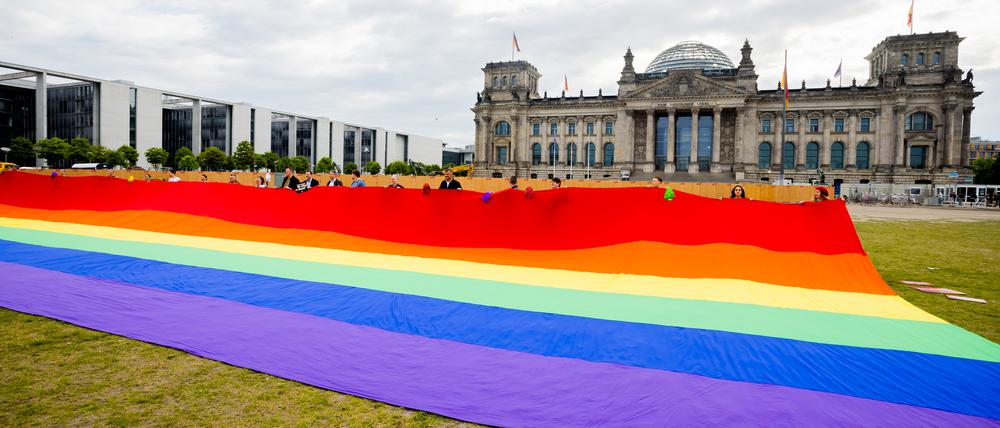 Teilnehmer einer Aktion der Initiative „Grundgesetz für Alle“ halten vor dem Reichstagsgebäude eine riesige Regenbogenfahne.