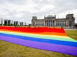 Teilnehmer einer Aktion der Initiative „Grundgesetz für Alle“ halten vor dem Reichstagsgebäude eine riesige Regenbogenfahne.