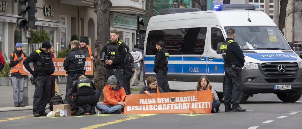  Aktivisten der Gruppe „Letzte Generation“ haben sich auf der Neuen Kantstraße auf einer Kreuzung festgeklebt.