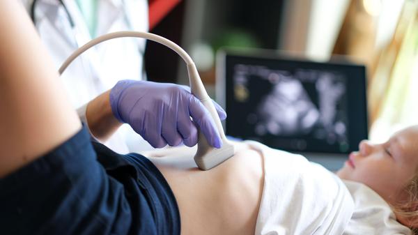 Arzt untersucht mit Ultraschall die inneren Organe eines Kindes in der Klinik