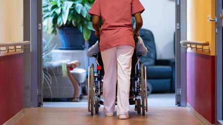 Eine Bewohnerin eines Pflegeheims wird von einer Pflegerin einen Gang entlang geschoben (Symbolbild).