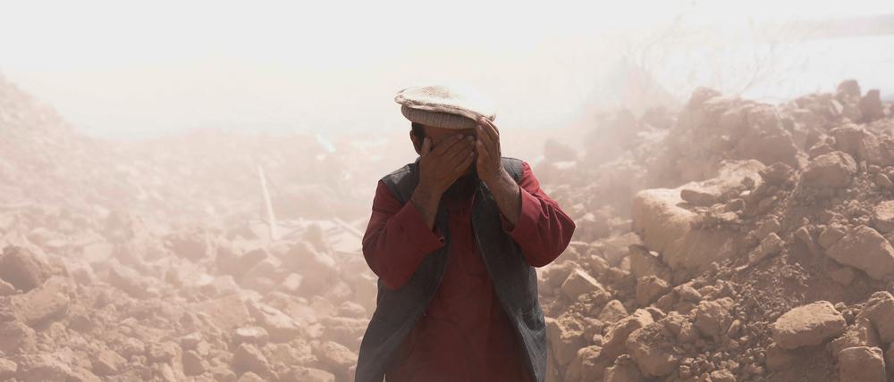 Ein Afghane bedeckt sein Gesicht, um sich vor dem Staub nach dem Erdbeben zu schützen.