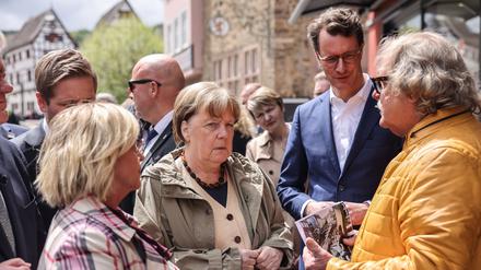 Die ehemalige Bundeskanzlerin Angela Merkel (M, CDU), Hendrik Wüst (2.v.r. CDU), Ministerpräsident Nordrhein-Westfalen, Bürgermeisterin Sabine Preiser-Marian (l, CDU) sprechen in Bad Münstereifel mit dem Cafehaus Besitzer Günter Portz (r).