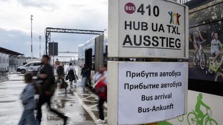 Menschen steigen aus dem BVG-Shuttel und gehen an Schildern mit Informationen auf Deutsch und Ukrainisch vorbei. Die Flüchtlingsunterkunft auf dem ehemaligen Flughafen Tegel beherbergt rund 2500 Menschen. (zu dpa «Berliner Senatorin stellt Verteilmechanismus für Flüchtlinge infrage») +++ dpa-Bildfunk +++