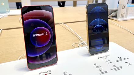 Ein iPhone 12 (l) und ein iPhone 12 Pro stehen in einem Apple Store auf einem Tisch.