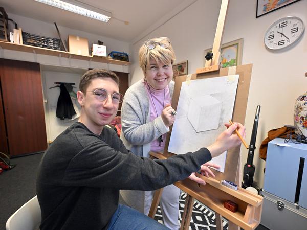 Lehrerin Natalia Kovalenko unterrichtet Arsenii Shapiro beim Zeichnen.