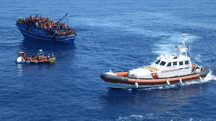 Die italienische Küstenwache (rechts) beobachtet vor der Küste Siziliens die Rettungsaktion der Organisation „Ärzte ohne Grenzen“, die Migranten und Flüchtlinge im Mittelmeer von einem Boot in Seenot retten. 