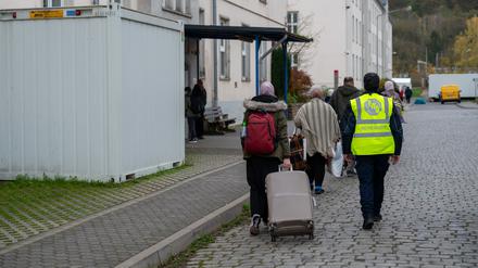 Neu angekommene Flüchtlinge gehen mit ihren Koffern in eines der Wohnhäuser der Aufnahmeeinrichtung für Asylbegehrende (AfA) in Trier.