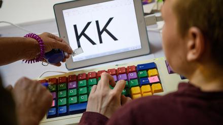 Eine Therapeutin übt mit einem autistischen Kind das Erkennen und Schreiben von Buchstaben auf einer Tastatur. (Symbolfoto)