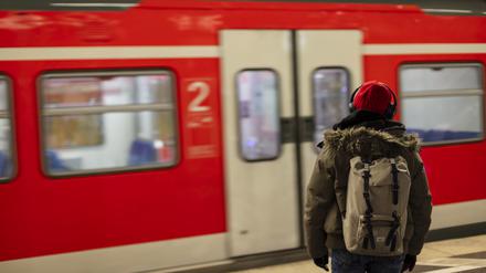 A man with a red cap and headphones waiting for the S-Bahn train at the Munich main train station.